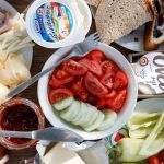 Delicious breakfast setup with cheese, cold cuts, bread, and fresh vegetables.